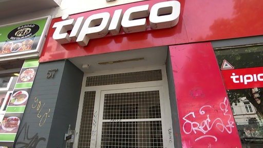 Ein Geschäft vom Sportwettenanbieter Tipico mit roter Fassade und weißem Schriftzug. Der Laden ist geschlossen und die Tür vergittert. 