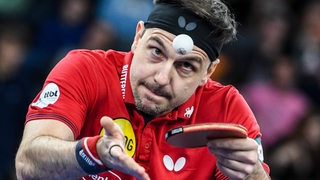 Tischtennis-Profi Timo Boll fokussiert beim Aufschlag den in die Luft geworfenen Ball.