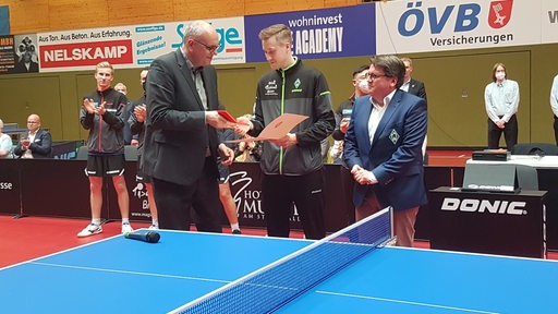Bremens Bürgermeister Andreas Bovenschulte überreicht Werders Tischtennis-Profi Mattias Falck die Senatsmedaille vor dem Spiel.