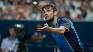 Tischtennis-Profi Kirill Gerassimenko von Werder Bremen fukussiert beim Aufschlag mit weit aufgerissenen Augen den hochgeworfenen Ball bei einem Spiel während der Olympischen Spiele in Paris.