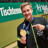 Werders Tischtennis-Spieler Mattias Falck deutet lächelnd auf die Goldmedaille um seinen Hals.