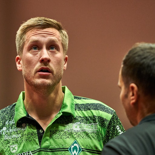 Werders Tischtennis-Profi Mattias Falck schaut bei einer Auszeit im Gespräch mit Trainer Cristian Tamas enttäuscht nach oben.