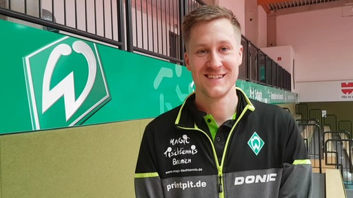 Werders Tischtennis-Profi Mattias Falck lächelt bei einem Interview in der Sporthalle.