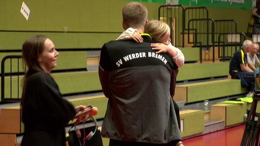 Werders Tischtennis-Profi Mattias Falck hält nach dem Sieg seine kleine Tochter im Arm, neben ihm seine Frau.