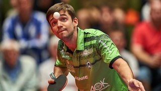 Werders Tischtennis-Profi Kirill Gerassimenko fixiert konzentriert den hochgeworfenen Ball vor seinem Gesicht beim Aufschlag.