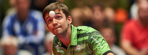 Werders Tischtennis-Profi Kirill Gerassimenko fixiert konzentriert den hochgeworfenen Ball vor seinem Gesicht beim Aufschlag.