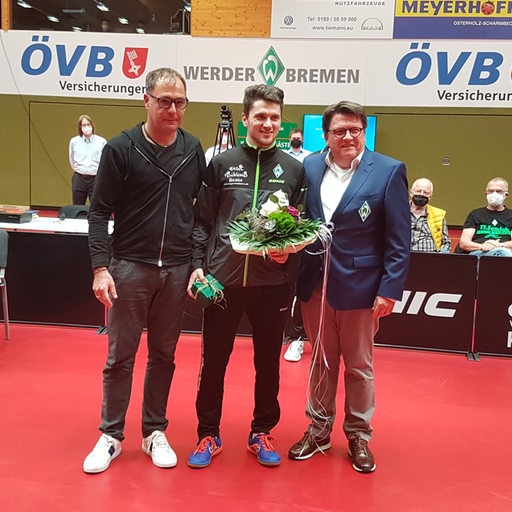 Tischtennis-Profi Hunor Szöcs wird mit Blumen von Werder-Präsident Hess-Grunewald und Manager Sascha Greber verabschiedet.