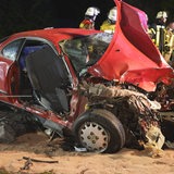 Ein komplett zerstörtes Auto liegt auf einer Fahrbahn.