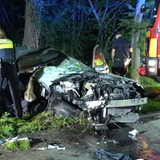 Ein komplett zertrümmertes Auto steht neben der Straße, davor stehen zwei Polizisten.