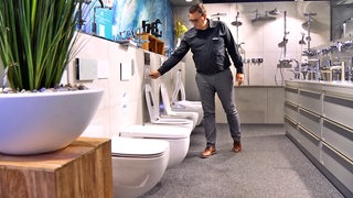 Ein Verkäufer führt eine neue Toilette vor.