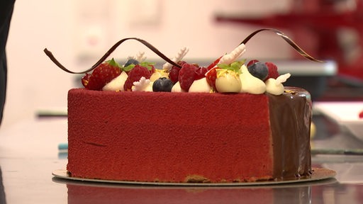 Eine rote Torte, dekoriert mit Beeren und Schokolade.