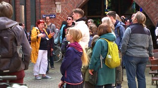 Eine Fremdenführerin führt eine Gruppe Touristen durch die Bremer Böttcherstraße.