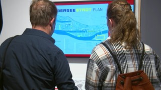Zwei Personen stehen vor einem großen Stadtplan von der Überseestadt in Bremen.