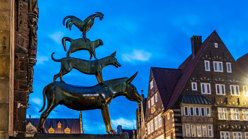Die Skulptur von den Bremer Stadtmusikanten ist in der Abenddämmerung zu sehen.