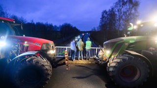 Zwei Traktoren stehen auf einer Autobahnbrücke
