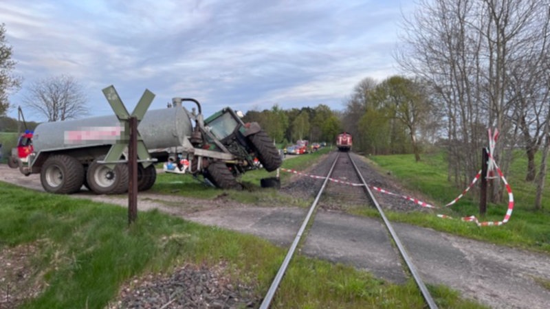 Ein Traktor steht nach einer Kollision mit einem Zug neben den Gleisen.