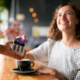 Eine junge Frau bezahlt in einem Café mit einer Visa-Karte.