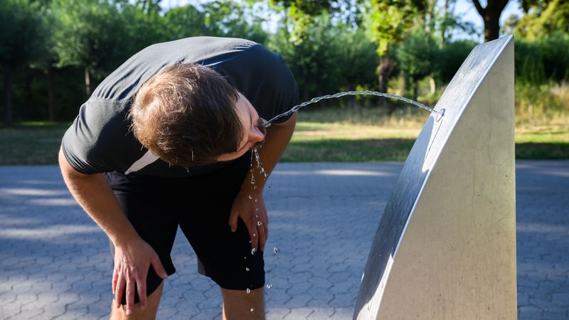 Ein Sportler trinkt Wasser an einem öffentlichen Trinkwasserspender