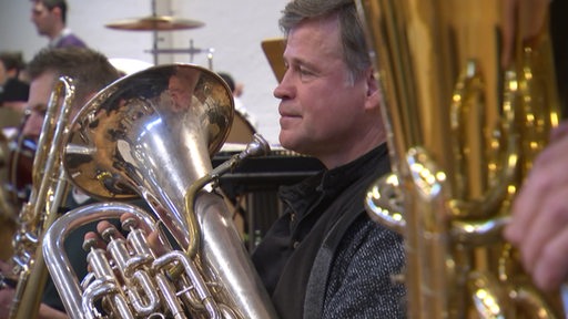 Ein Mann spielt Tuba im Blasorchester.