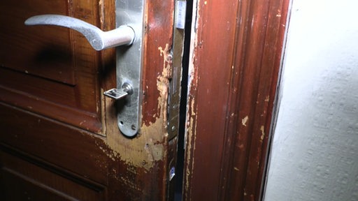 Es ist eine beschäfigte Tür zu sehen, welche um das Türschloss herum Kratzer und abgesplittete Farbe hat.