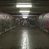 Zu sehen ist ein mit Grafittis beschmierter dunkler tunnel.