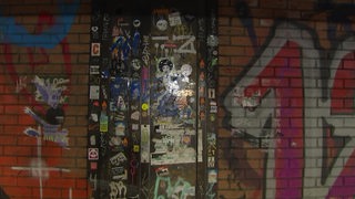 Eine geheimnisvolle Tür mit Stickern beklebt, in einem Tunnel in Findorff.