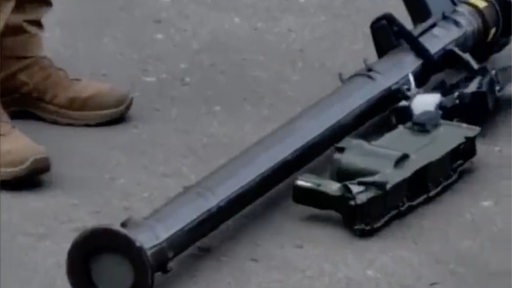 Ein Mann steht neben einer Panzerabwehrwaffe, die auf dem Boden liegt (Screenshot)