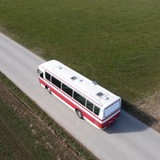 Ein rot-weißer Bus fährt eine Straße entlang