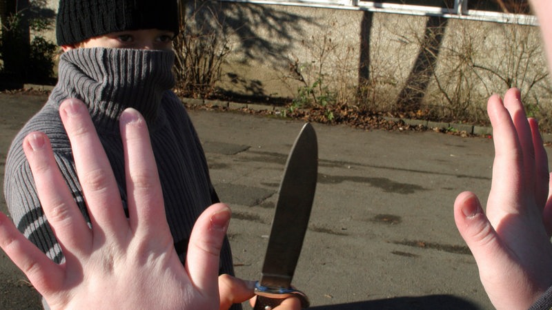 Ein maskierter Mann droht mit einem Messer