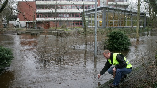 Ein Mitarbeiter der Stadt Delmenhorst kontrolliert im Januar 2008 den Pegel der über die Ufer getretenen Delme vor dem Gymnasium in der Delmenhorster Innenstadt. 