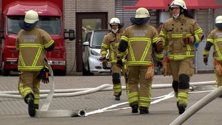 Feuerwehrleute legen bei einem Einsatz Schläuche aus.