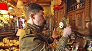 Der Uhrenrestaurateur Lucas Rupprecht beschaut eine antike Uhr.