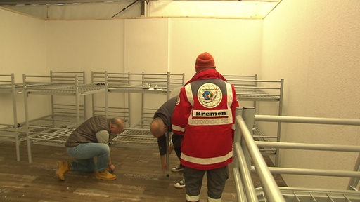 Freiwillige und Mitarbeitende des Deutschen Roten Kreuz und der Malteser bauen die Betten in den Zelten in der Überseestadt auf. 