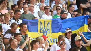 Während des Länderspiels zwischen Deutschland und der Ukraine halten Fans eine ukrainische Flagge hoch.