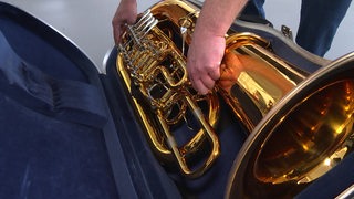 Ein Blasinstrument  wird für einen Umzug im Koffer verstaut.