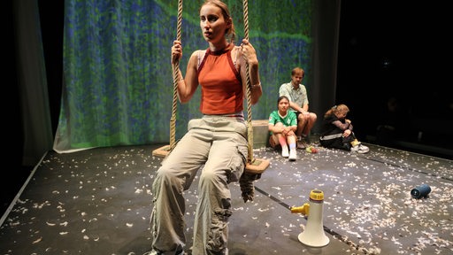 Theaterszene mit einem traurigen Mädchen auf einer Schaukel im Vordergrund