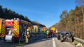 Auf einer Autobahn stehen Rettungsfahrzeuge und ein Autowrack.