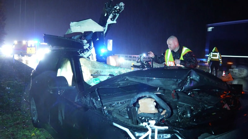 Ein Polizist untersucht das Wrack eines Unfallwagens auf der A1 bei Wildeshausen.