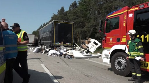 Eine Unfallstelle auf der Autobahn mit zerstörten Autos und der Feuerwehr. 