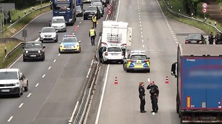 Nach einem Unfall auf der B75 zwischen Bremen und Delmenhorst staut sich der Verkehr, Polizisten stehen hinter den Unfallfahrzeugen auf der Straße.