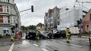 Mehrere Rettungskräfte sind an einer Kreuzung bei drei verunfallten Autos im Einsatz.