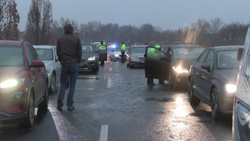 Mehrere Autos stehen bei Glatteis auf einer Straße nach einem Unfall.