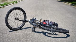 Auf einer Straße liegt ein umgekipptes Fahrrad.