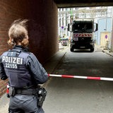 In einer Einfahrt steht ein Müllwagen, davor ist eine Polizistin zu sehen.