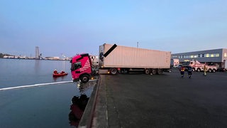 Die Fahrerkabine eines Lkw ragt ins Hafenbecken.