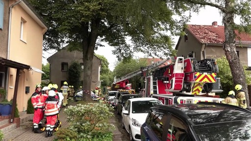 Die Feuerwehr mit Einsatzwagen und versammelter Mannschaft an der Unfallstelle eines explodieren Reihenhauses.