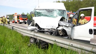 Mehrere Einsätzkräfte der Feuerwehr stehen bei einem zerstörten Kleintransporter auf der A1.