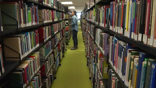 Janos Keresziti auf Büchersuche zwischen den Regalen der Unibibliothek