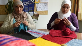 Zwei Frauen stricken in einer Flüchtlingsunterkunft.