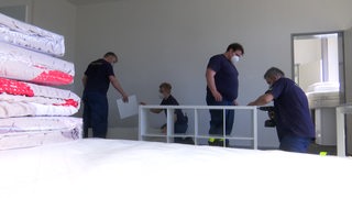 Frewillige Helfer, die Möbelstücke aufbauen, für die Unterkunft von Geflüchteten. 
